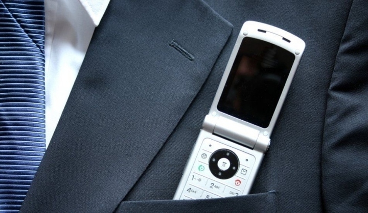 Mobilní telefon, který je zastrčen v klopě pánského obleku