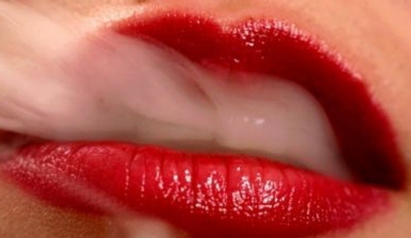 Detailní fotografie ženských úst vyfukující kouř z cigaret