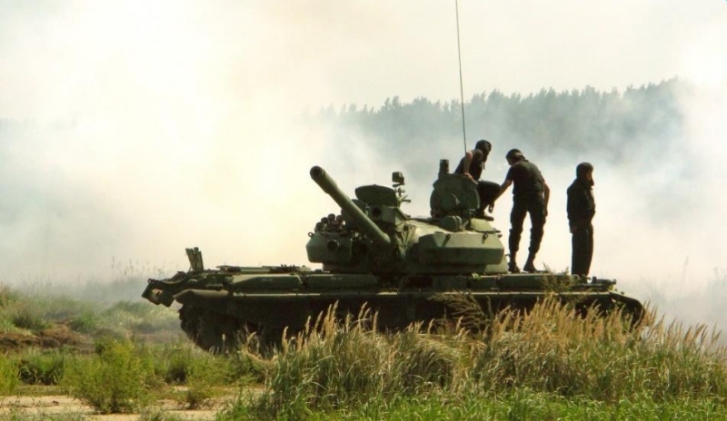 Fotografie tanku se třemi  tankisty na zeleném poli