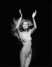 Černobílá fotografie nahé ženy s rukama nad hlavou
