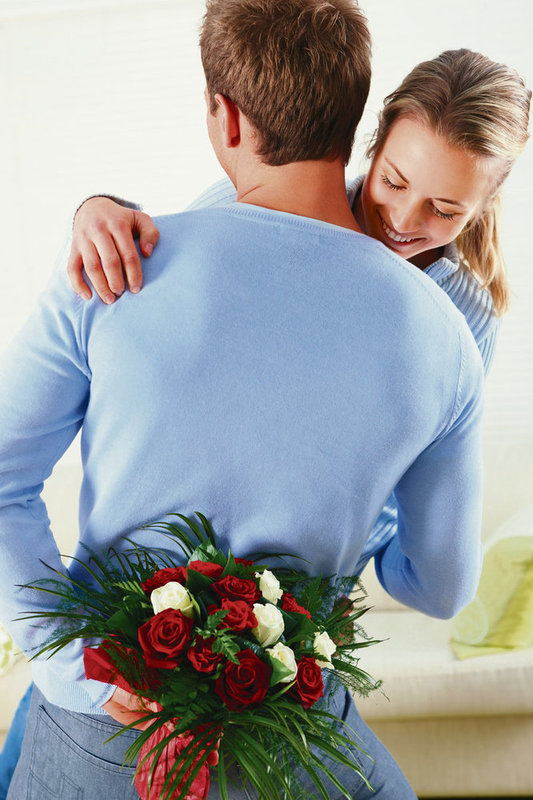 Fotografie muže s kyticí růží za zády objímající ženu