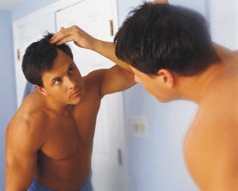 Fotografie muže, který si kontroluje vlasy v zrcadle