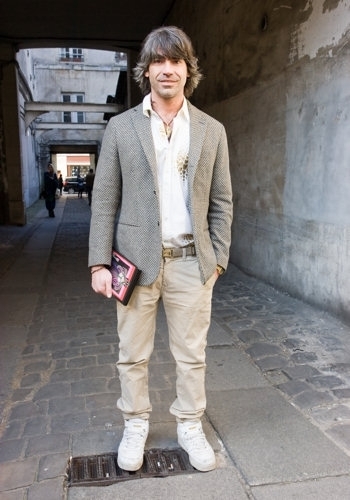 Muž stojící na ulici v saku a kalhotech