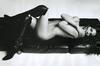 Černobílá fotografie nahé ležící ženy v černých kozačkách