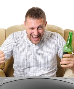 Muž sedící v křesle s pivem v ruce