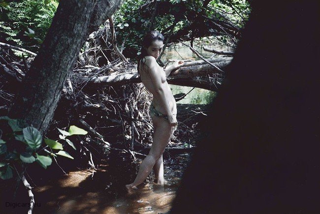 Nahá žena stojící ve vodě mezi stromy