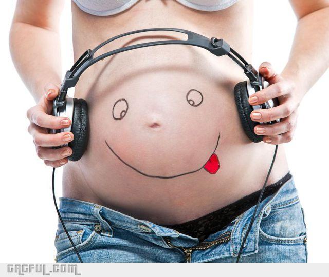 Těhotná žena s pokresleným břichem a se sluchátky na břiše